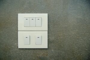 Minimalist photo of white electrical rocker switches on a textured stone wall background.