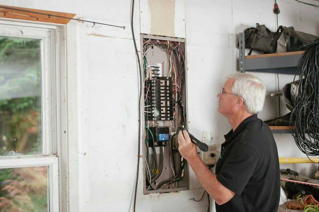 An electrician carefully examines a residential fuse box indoors, ensuring electrical safety and compliance.