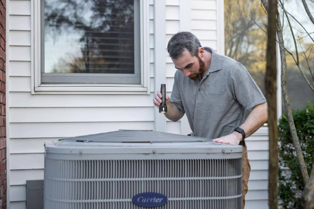 A technician inspects an outdoor HVAC unit for maintenance.