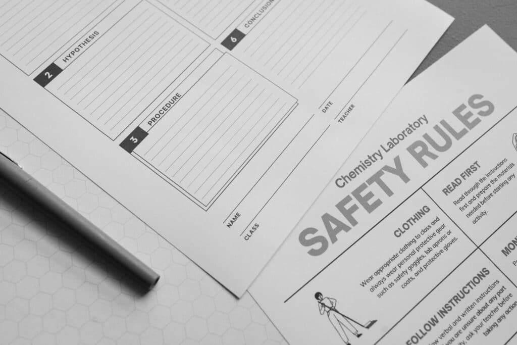 Black and white image of chemistry lab safety and procedure sheets with pen in view.